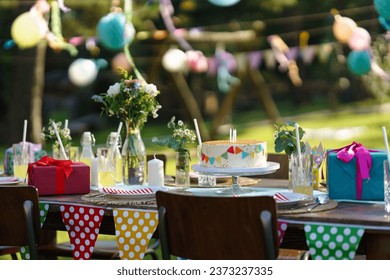 Shot of the birthday table with colorful decorations, birthday cake, and gifts. Inspiration for simple, tasteful birthday decoration for a garden party. - Powered by Shutterstock