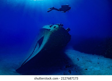 A shot of the bow section of the sunken shipwreck Kittiwake in the tropical waters of the Cayman Islands. A silhouette of a lone diver can be seen floating above the bow underneath the light beams