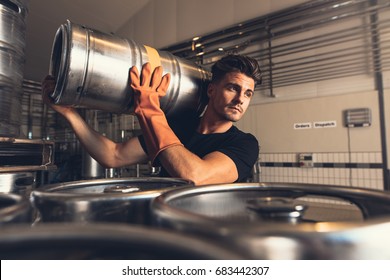 Shot of brewer carrying keg at brewery factory. Young man with metal beer barrels at warehouse. - Powered by Shutterstock