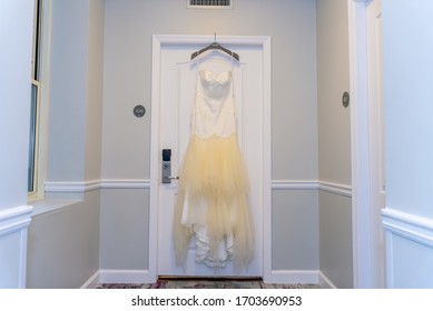 A Shot Of A Bridal Dressing Room With A Bridal Gown Hanging On The Hanger On The Door Frame