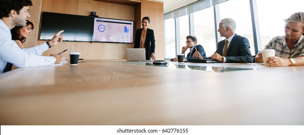 Shot Of Business People Having Board Meeting In Modern Office. Young Executive Asking Some Questions To Woman.