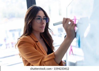 Shot Of Business Young Woman Working On White Board With Post It Stickers In The Office.