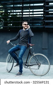 Shot of a businessman using his cellphone while going to work with his bicycle. Selective focus, narrow depth of field. - Shutterstock ID 325569131