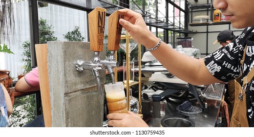 A Shot Of A Cafe Worker Pouring A Nitro Cold Brew Coffee From The Tap To A Cold Glass Before Serving To Customer In Bangkok, Thailand On 8th July 2018