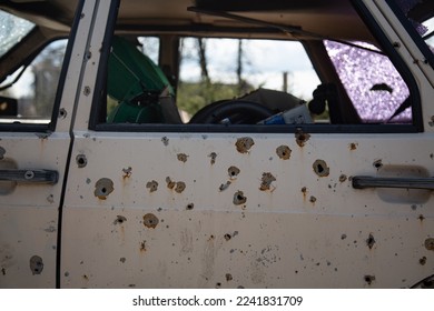Shot car. Destroyed automobile. A pile of metal. After the shooting. The war in Ukraine. Traces of bullets. Broken glass.