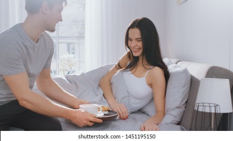 Shot Of A Caring Young Man Bringing Tray With Breakfast In Bed To His Lovely Female Partner. Ideal Tender Relationship And Coffee And Croissants In Bed.