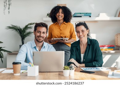 Shot of casual business people looking at camera while working in the new office. - Powered by Shutterstock