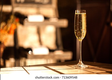 Shot of the champagne glass on a wooden table. Sunlight and bubbles.