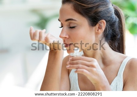 Shot of a cheerful woman girl holding a bottle of essential oil while testing it sitting on a couch at home.