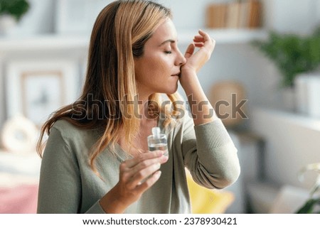Shot of a cheerful woman holding a bottle of essential oil while testing it sitting on a couch at home.