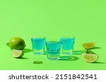 Shot cocktails and limes on color background
