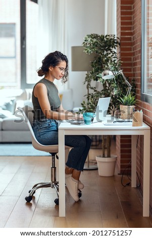 Shot of concentrated business woman working with laptop in living room at home.