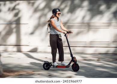 Shot of confident cheerful woman riding electric push scooter through the city - Powered by Shutterstock