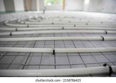 Shot Of Construction Site In A Loft Where Underfloor Heating Has Just Been Installed, White Pipes On Grey Mat