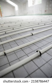 Shot Of Construction Site In A Loft Where Underfloor Heating Has Just Been Installed, White Pipes On Grey Mat