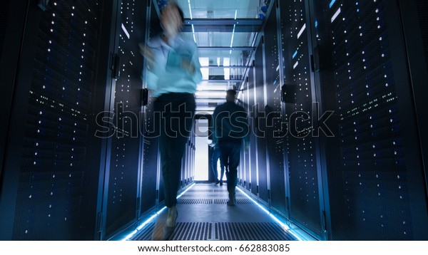 Shot of Corridor in Large\
Data Center Full of Walking and Working People. Pronounced Motion\
Blur.