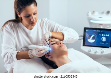 Shot of cosmetologist making ultrasonic cleaning and rejuvenation the face to beautiful woman on the spa center. - Powered by Shutterstock