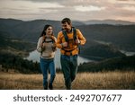 Shot of a couple going for a hike up the mountain, lake in the background