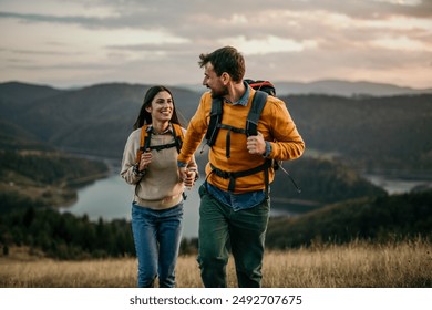 Shot of a couple going for a hike up the mountain, lake in the background - Powered by Shutterstock