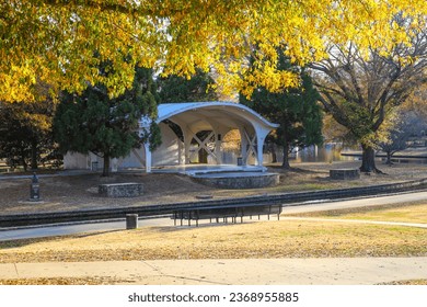 a shot of a curvy white amphitheater in the park surrounded by gorgeous autumn colored trees near a lake with a long smooth winding footpath at Freedom Park in Charlotte North Carolina USA	