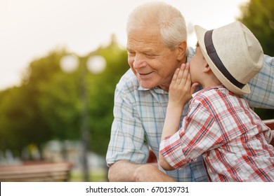 Shot of a cute little boy whispering something to his grandfather while resting together outdoors copyspace family communication relationships trust happiness love gossip children kids parenting - Powered by Shutterstock