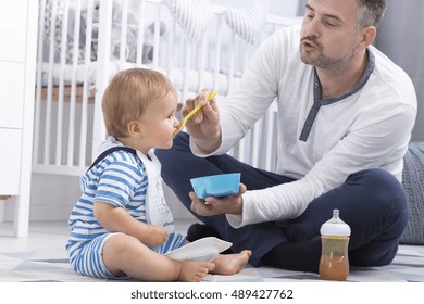 Shot Of A Dad Feeding His Baby In A Nursery Room