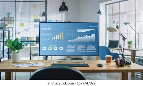 Shot Of A Desktop Computer In The Creative Modern Office. Monitor Screen Shows Company Growth Data With Graphs, Charts, Software UI.