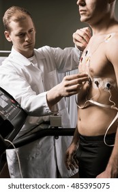 Shot of a doctor in white uniform attaching electrodes to his patient's body