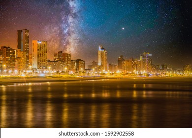 Shot Of Durban City Skyline From Ocean With Illuminated Beach Front Buildings And Milky Way Galaxy In The Sky