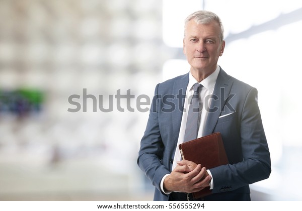 Shot of an elderly managing\
director with diary standing in conference room after business\
meeting. 