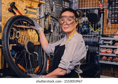 Shot Of Elderly Woman Mechanic Repairing Bicycle Wheel On Workbench In Repair Shop.