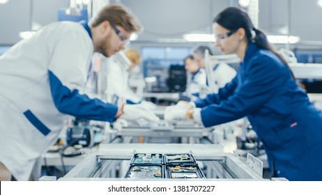 Shot Of An Electronics Factory Workers Assembling Circuit Boards By Hand While It Stands On The Assembly Line. High Tech Factory Facility.