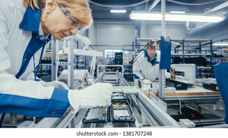 Shot of an Electronics Factory Workers Assembling Circuit Boards by Hand While it Stands on the Assembly Line. High Tech Factory Facility.