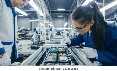 Shot of an Electronics Factory Workers Assembling Circuit Boards by Hand While it Stands on the Assembly Line. High Tech Factory Facility.