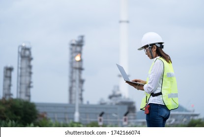 Shot Of Engineer Woman Wearing Work Helmet And Reflective Vest, Checking Data Using Laptop At Power Plant.