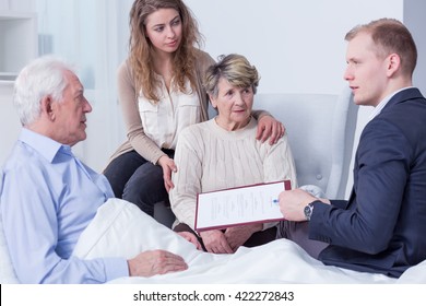 Shot Of A Family Listening To A Young Man Holding A Last Will Form