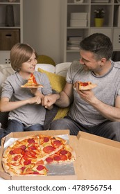 Shot Of Father And Son Eating Pizza In A Room