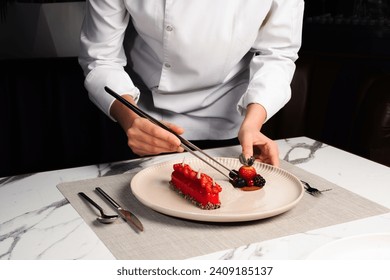 Shot of the female chef hold the kitchen tweezers and prepares dessert with red fruits for serving.  - Powered by Shutterstock