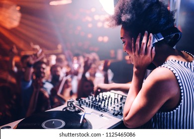 Shot of a female DJ playing music in the club