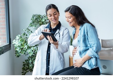 Shot of female gynecologist doctor showing to pregnant woman ultrasound scan baby with digital tablet in medical consultation. - Powered by Shutterstock