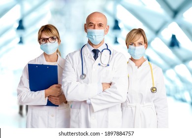 Shot of female and male doctors wearing face masks and standing together on the clinic’s foyer while looking at camera. Medical team. Doctors wearing face masks for prevention.