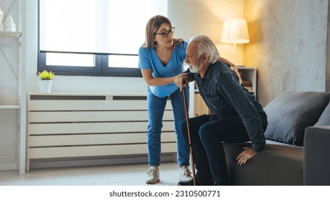 Shot of a female nurse helping her elderly male patient. Smiling senior man with female healthcare worker. Home carer supporting old man to stand up from the chair at care home. - Powered by Shutterstock