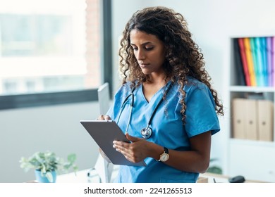 Shot of female nurse using her digital tablet while standing in the consultation. - Powered by Shutterstock