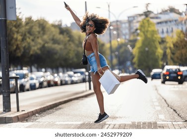 Shot of funny crazy woman jumping while holding smartphone crossing the street. - Powered by Shutterstock