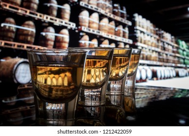 Shot glasses on bar in tasting distillery with barrels in background