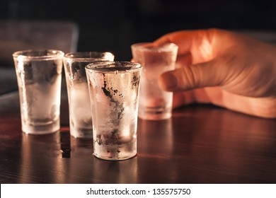 Shot glasses of vodka on a wooden table, addiction to alcohol. - Shutterstock ID 135575750