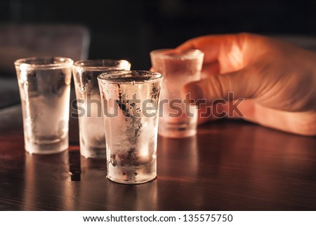 Shot glasses of vodka on a wooden table, addiction to alcohol.