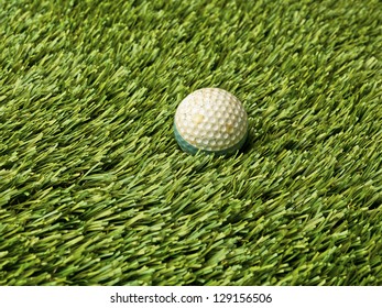 Shot Of A Golf Ball Laying In Green Astroturf.