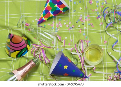 Shot Of A Green Tablecloth After A Party Celebration With Confetti, Empty Bottle Of Champagne, Champagne Glass With Lipstick,imprint,  Glass With Whiskey And Party Poppers