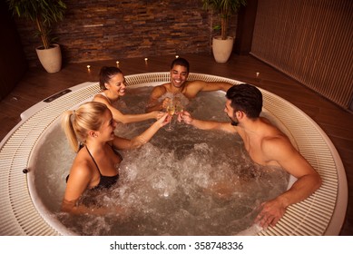 Shot of a group of friends drinking champagne and relaxing in jacuzzi.